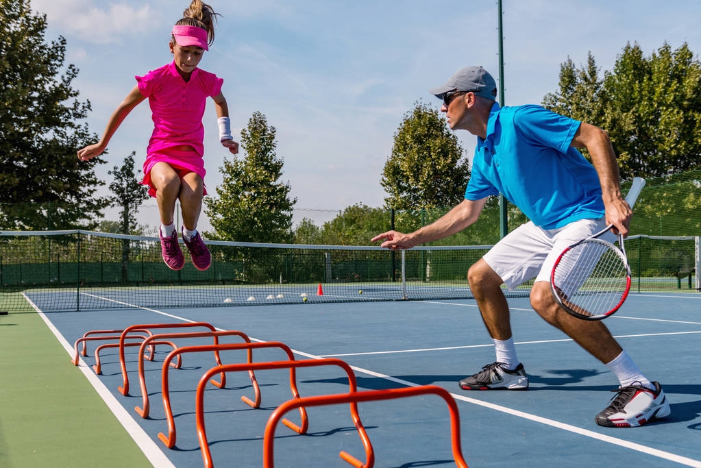 stock-photo-male-trainer-girl-tennis-training (1)