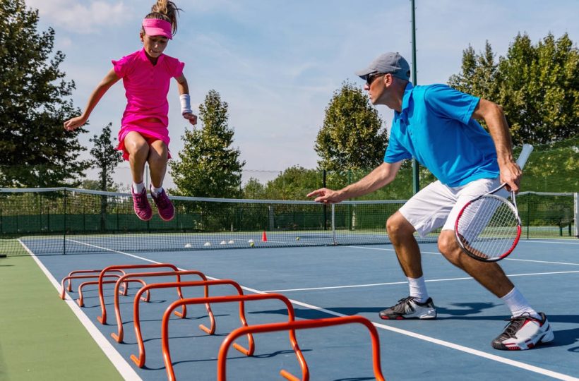 stock-photo-male-trainer-girl-tennis-training (1)